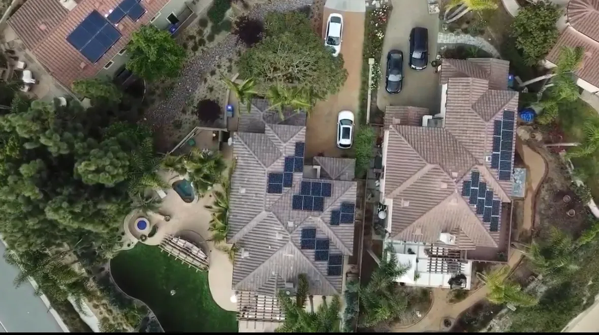 Aerial view of residential neighborhood with solar panels and well-maintained landscaping in North County San Diego