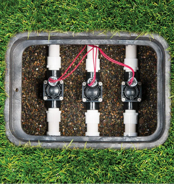 Irrigation valves in valve box on green lawn